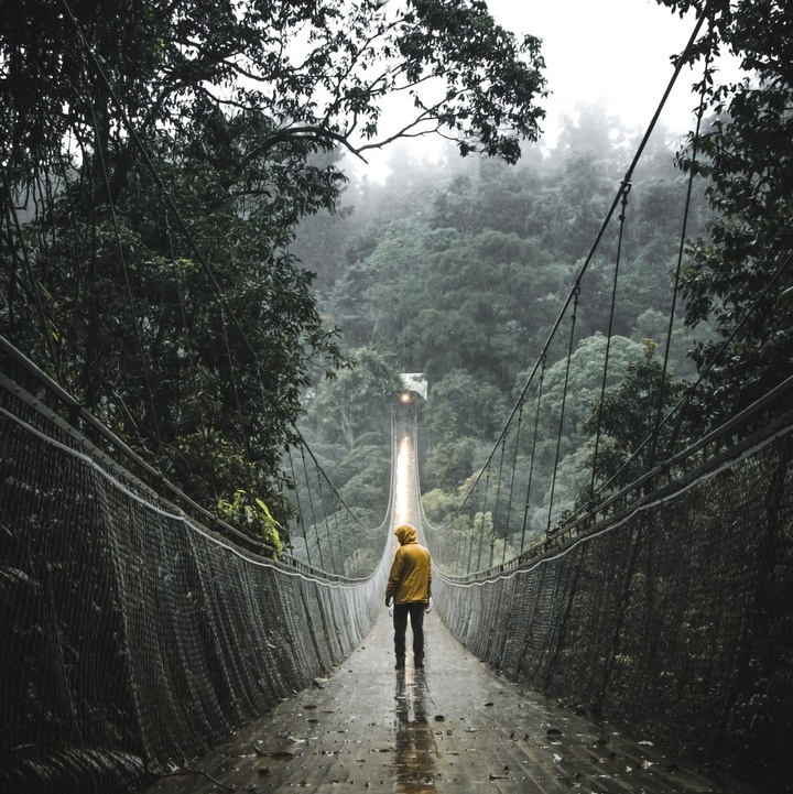 Person auf einer Hängebrücke im Nebel