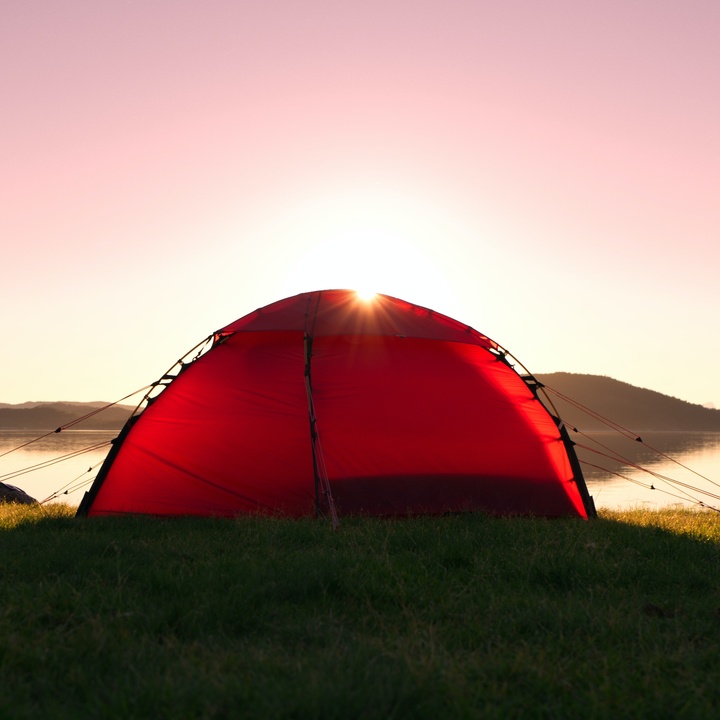 Einzelnes Zelt vor Sonnenaufgang am See