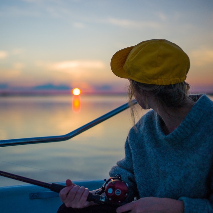 Anglerin in Boot bei Sonnenuntergang