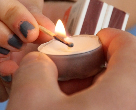 Menschen entzünden eine Kerze